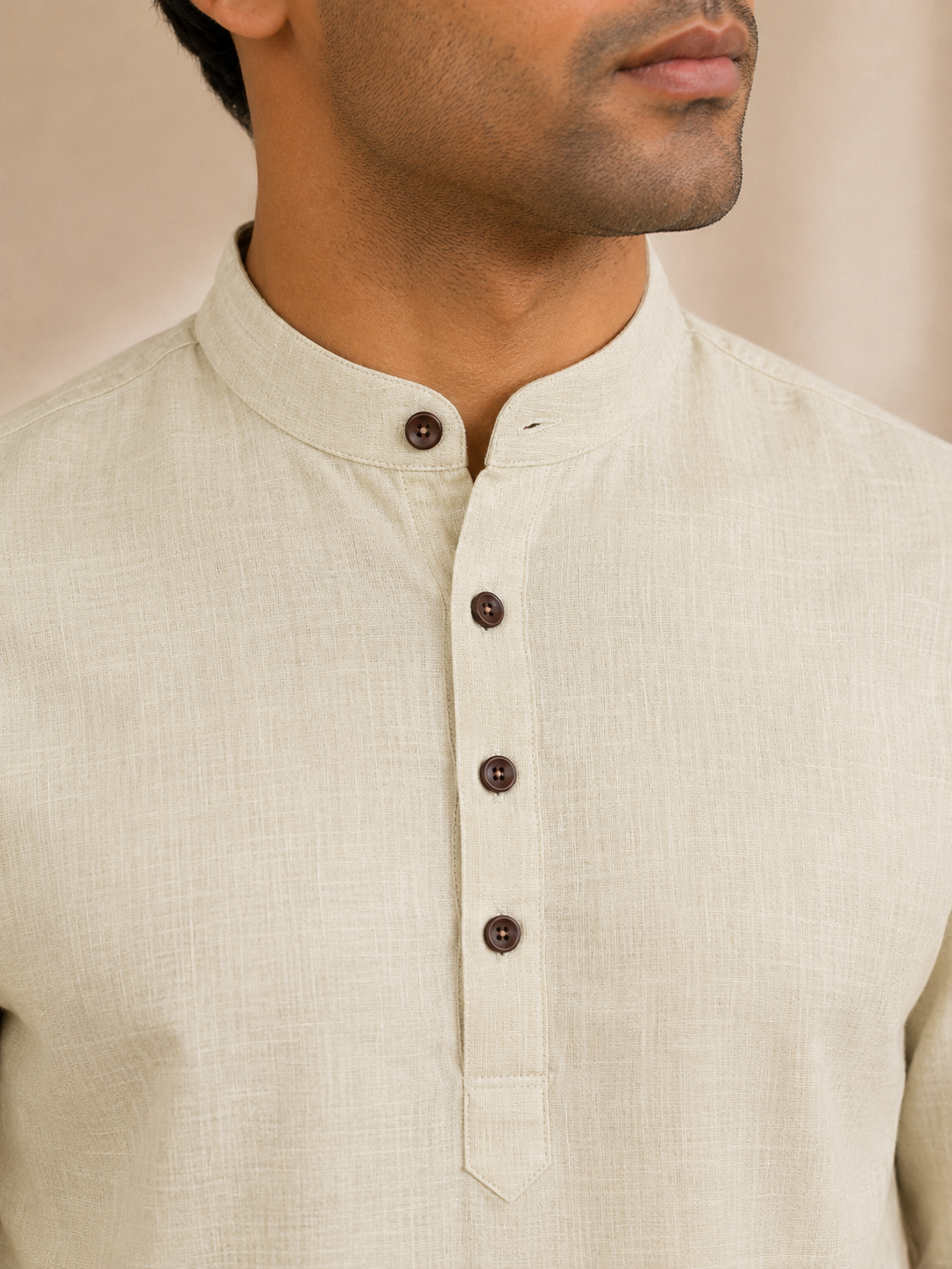 Close-up of a man wearing a pale lime linen kurta with a mandarin collar and a three-button placket.