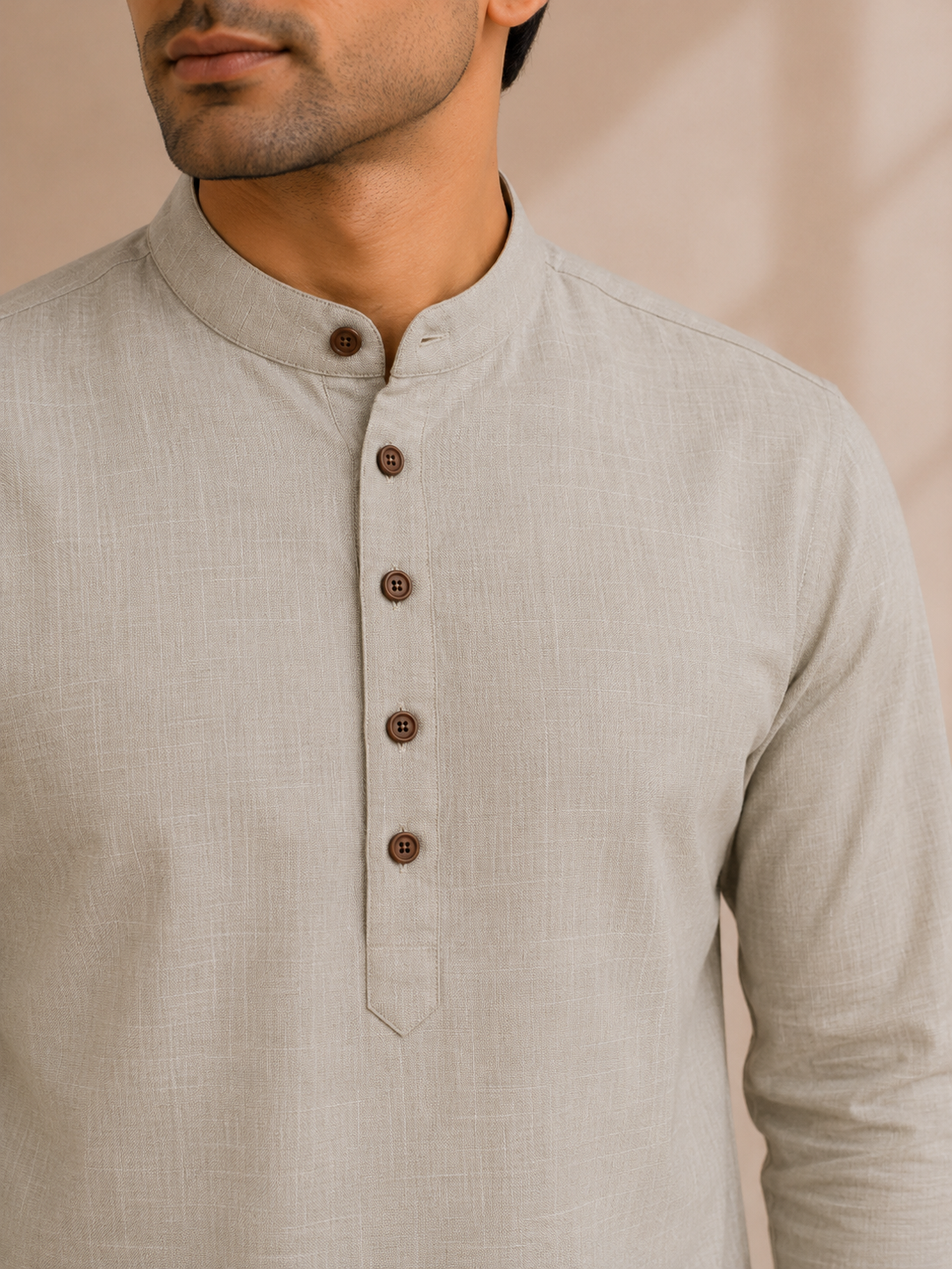 Close-up of a man wearing a light beige linen long-sleeve kurta with a mandarin collar and a button placket.